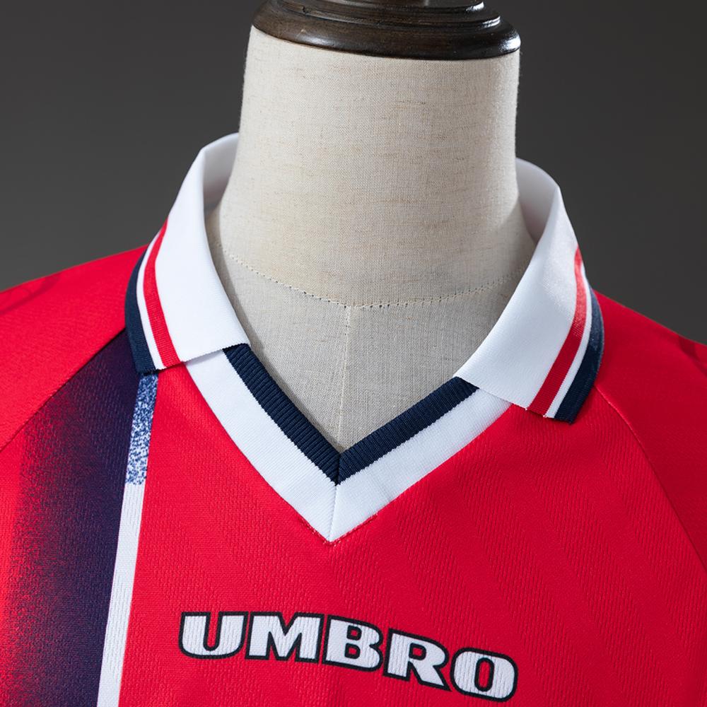 Nærbilde av V-halsen og den broderte Umbro-logoen på den klassiske norske hjemmedrakten fra 1997