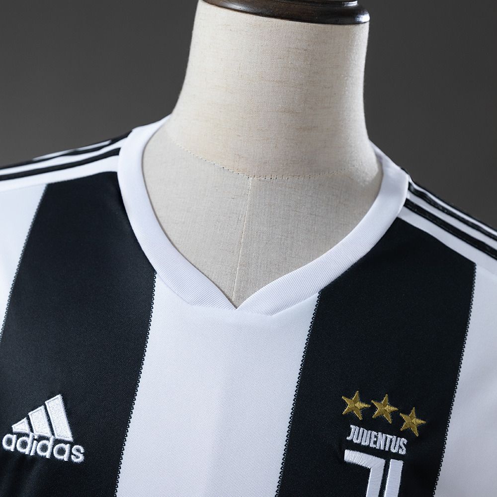 Hvit V-hals og Juventus-merke med tre gullfargede stjerner over de brede svarte stripene