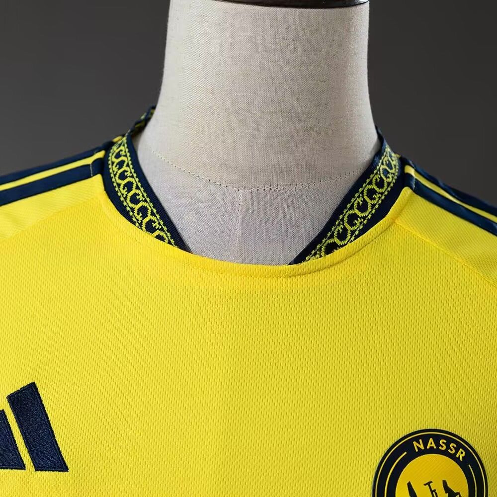 Nærbilde av gul Al-Nassr hjemmedrakt 26/27 med mønstret mørkeblå krage