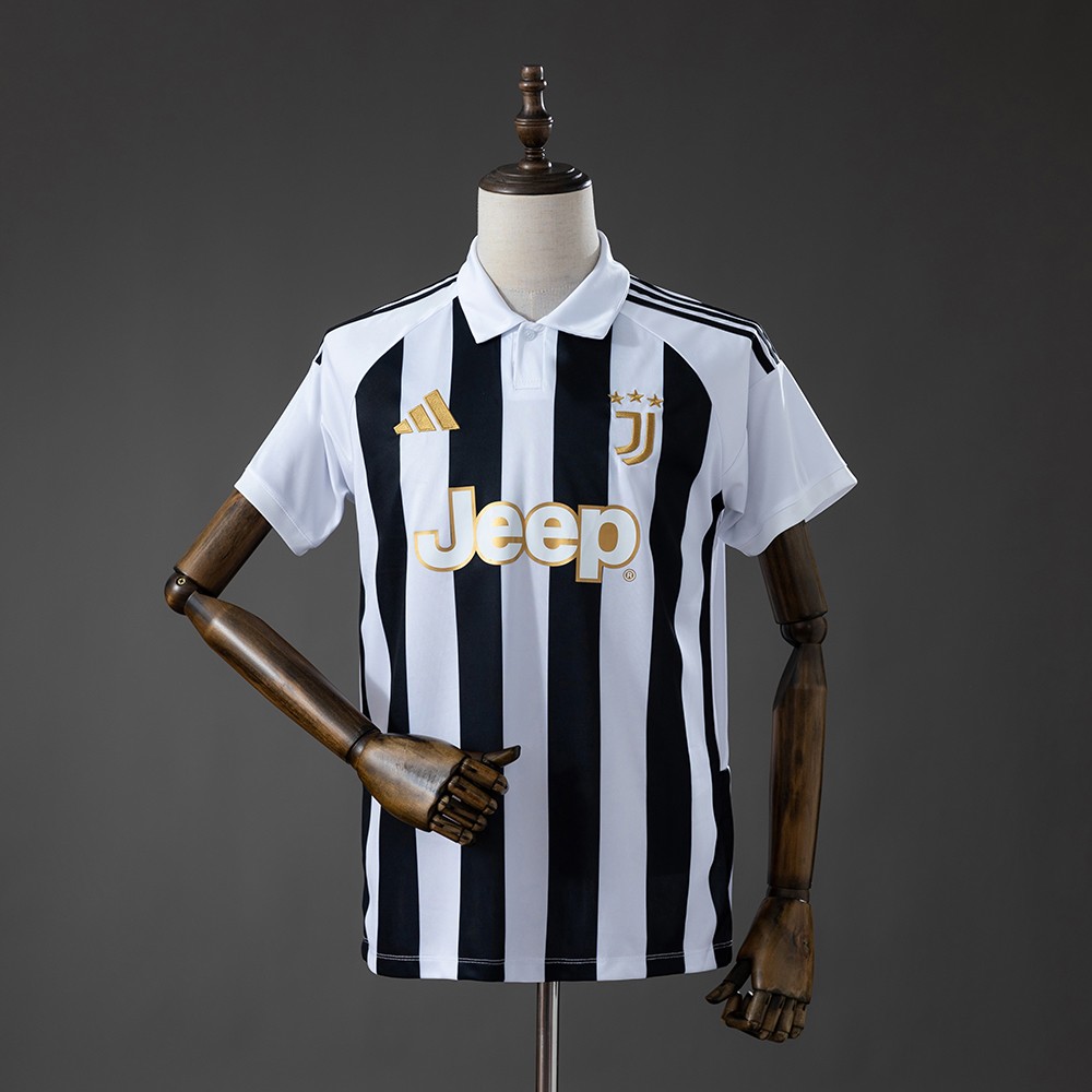 Svart-hvit Juventus hjemmedrakt 26/27 på dukke med korte hvite ermer, polokrage og gullfargede brystdetaljer