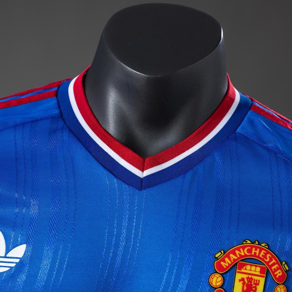 Nærbilde av V-hals og røde detaljer på Manchester United bortedrakt 26/27