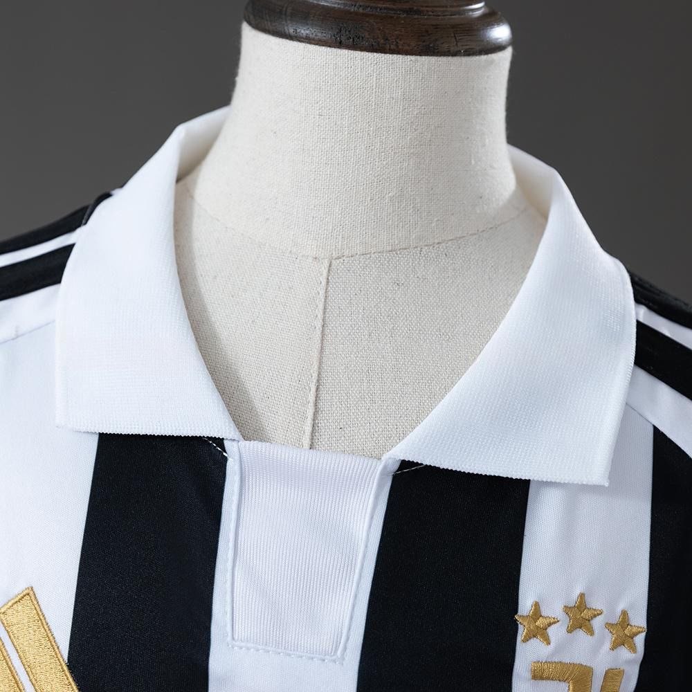 Hvit polokrage og gullfarget Juventus-merke med tre stjerner på den svart-hvite barnedrakten
