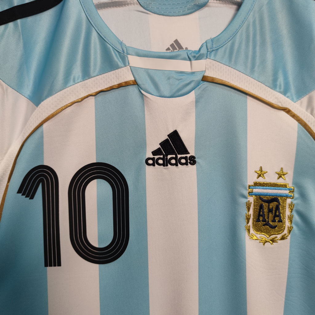 Detalj av nummer 10, to stjerner og gullfarget bue på Argentina 2006 hjemmedrakt