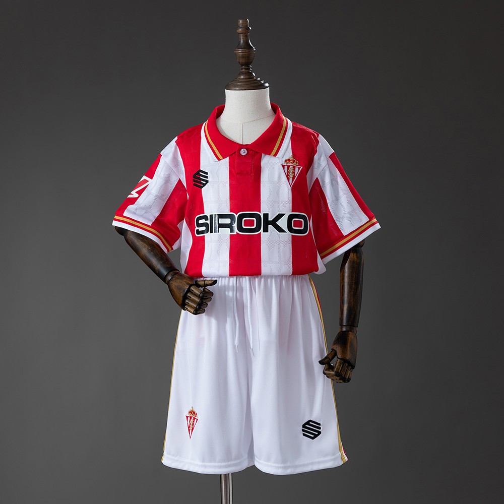 Sporting Gijón 2026/27 hjemmedrakt for barn med rød- og hvitstripet trøye og hvite shorts sett forfra